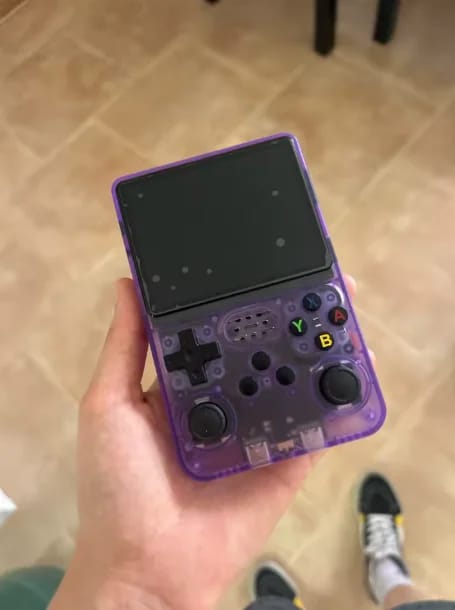 Consola portátil retro morada translúcida en la mano